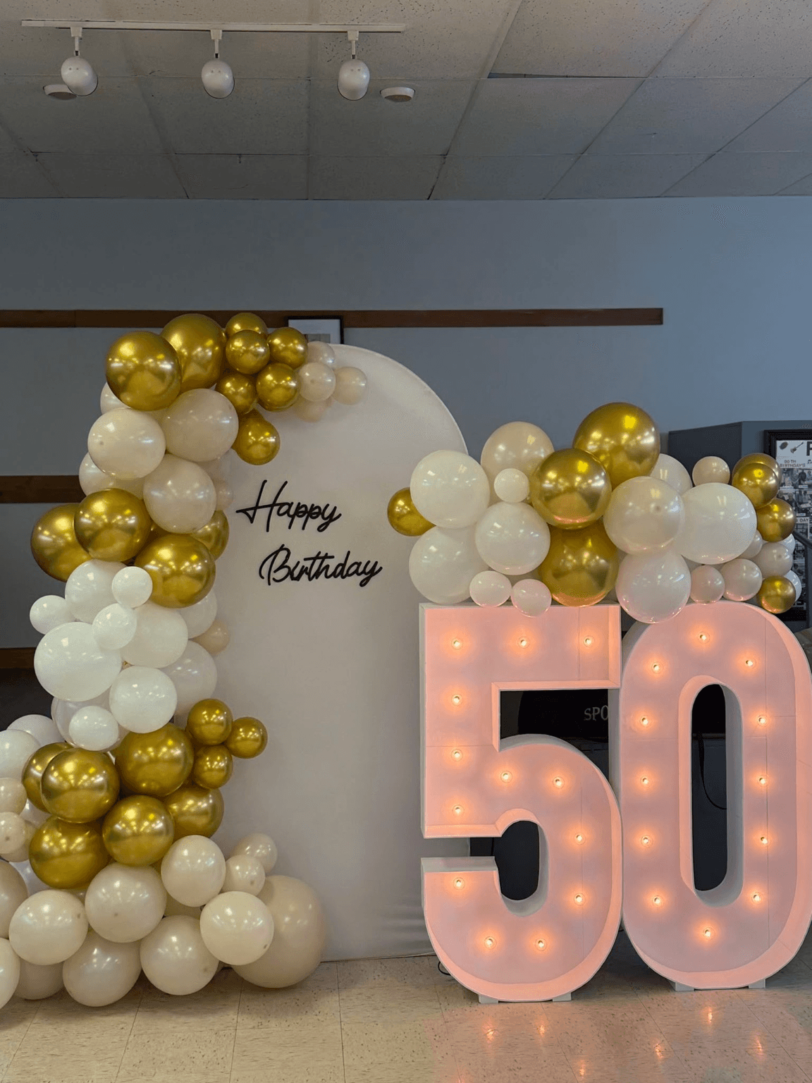 50th birthday backdrop with white and gold balloon garlands and illuminated marquee numbers styled by Star Events